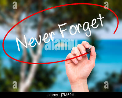 Man Hand writing Never Forget  with black marker on visual screen. Isolated on nature. Business, technology, internet concept. Stock Photo Stock Photo