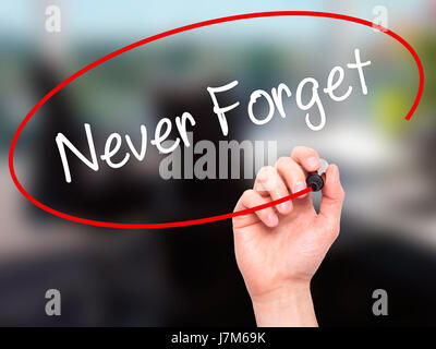 Man Hand writing Never Forget  with black marker on visual screen. Isolated on office. Business, technology, internet concept. Stock Photo Stock Photo