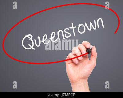 Man Hand writing Queenstown  with black marker on visual screen. Isolated on grey. Business, technology, internet concept. Stock Photo Stock Photo