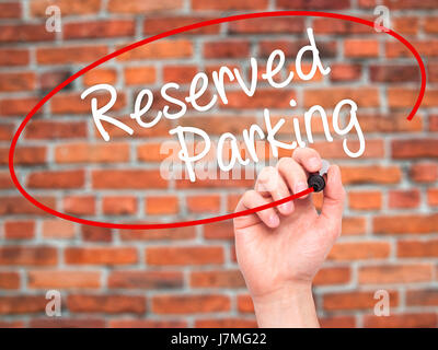 Man Hand writing Reserved Parking with black marker on visual screen. Isolated on bricks. Business, technology, internet concept. Stock Photo Stock Photo