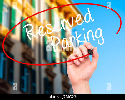 Man Hand writing Reserved Parking with black marker on visual screen. Isolated on city. Business, technology, internet concept. Stock Photo Stock Photo