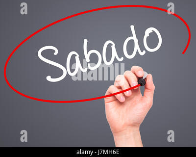 Man Hand writing Sabado (Saturday in Spanish/Portuguese) with black marker on visual screen. Isolated on grey. Business, technology, internet concept. Stock Photo