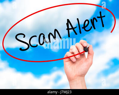 Man Hand writing Scam Alert  with black marker on visual screen. Isolated on sky. Business, technology, internet concept. Stock Photo Stock Photo