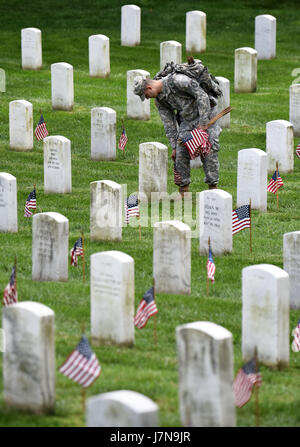 Arlington, USA. 25th May, 2017. A soldier from the 3rd U.S. Infantry Regiment places flags at grave sites during the 'Flags-In' ceremony at the Arlington National Cemetery in Arlington, Virginia, the United States, on May 25, 2017. More than 1,000 soldiers placed flags for over 284,000 graves in the cemetery ahead of Memorial Day, the last Monday of May. Credit: Yin Bogu/Xinhua/Alamy Live News Stock Photo