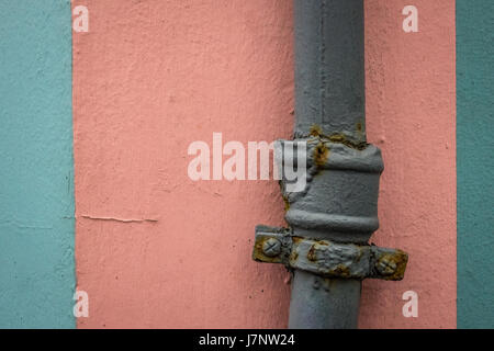 Old rusted water pipe on pink and blue wall texture background Stock Photo