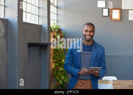 Smiling young African businessman using a tablet in an office Stock Photo