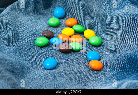 Colorful of chocolate little candies isolated on jeans blue background Stock Photo