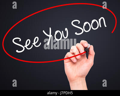 Man Hand writing See You Soon with black marker on visual screen. Isolated on background. Business, technology, internet concept. Stock Photo Stock Photo