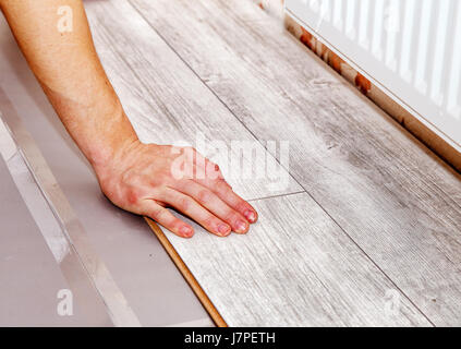 young handyman installing wooden floor in new house, hands closeup Stock Photo