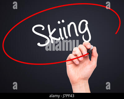 Man Hand writing Skiing with black marker on visual screen. Isolated on black. Business, technology, internet concept. Stock Photo Stock Photo