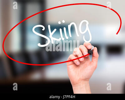 Man Hand writing Skiing with black marker on visual screen. Isolated on office. Business, technology, internet concept. Stock Photo Stock Photo