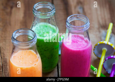 Fresh healthy three types of fruits juices or smoothies, orange, green and pink with strawberries, apricots,kiwi and spinach Stock Photo