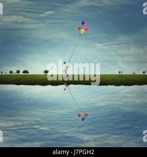 Young boy stand on a country meadow near the lake, holding some colorful balloons. Life joy, fun and happiness. Stock Photo