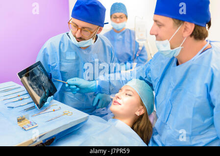 Dental team examining radiography of a young beautiful woman patient Stock Photo