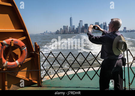 Male Tourist Taking Photo of Manhattan Skyline from the Staten Island Ferry, NYC, USA Stock Photo
