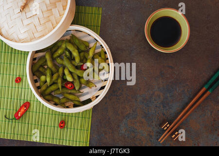 Spicy Edamame beans served warm with salt in bamboo steamer. Top view, blank space Stock Photo