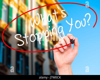 Man Hand writing What's Stopping You?  with black marker on visual screen. Isolated on city. Business, technology, internet concept. Stock Photo Stock Photo