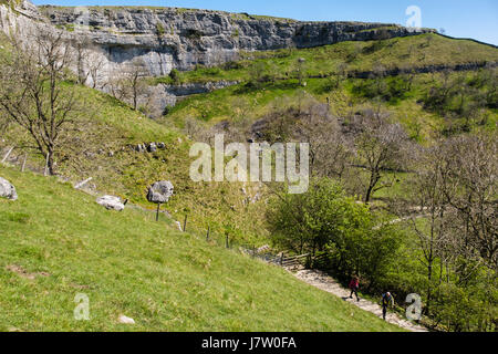 View of Malham Cove from Pennine Way path with people walking up. Malham, Malhamdale, Yorkshire Dales National Park, North Yorkshire, England, UK Stock Photo