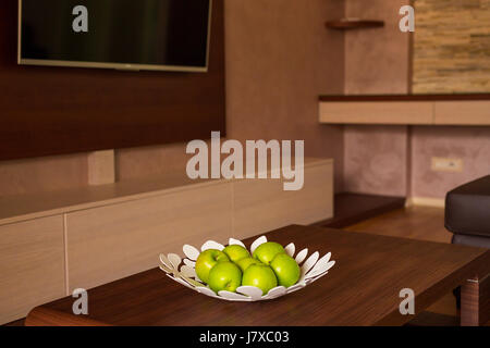 A plate with green apples on the table in apartment. Stock Photo