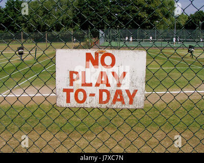 A 'no play today' sign on a fence at grass tennis courts at a club in Ealing, west London, England, UK in 2006. The hand-painted sign refers to 'TO-DAY' rather than the normal spelling of 'TODAY' Stock Photo