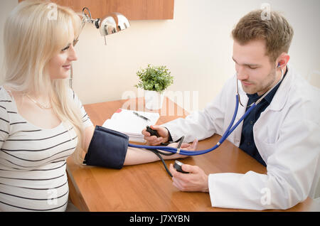 Young doctor checking blood pressure of female patient. pressure blood doctor patient medical heart sphygmomanometer measuring concept Stock Photo