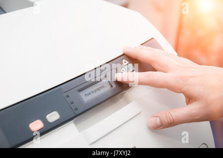 Man holding finger on start button of laser printer Stock Photo