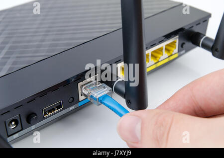 Man plugs internet cable into the router. router wifi ethernet connection network port wireless closeup concept Stock Photo
