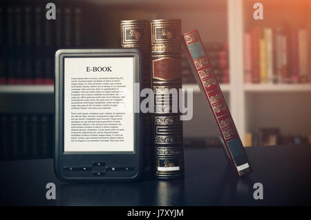 E-book reader device on desk in library. Alternative for traditional books Stock Photo