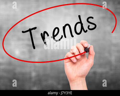 Man Hand writing Trends with marker on transparent wipe board. Isolated on grey. Business, internet, technology concept. Stock Photo Stock Photo
