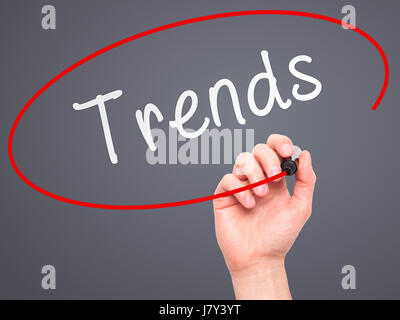 Man Hand writing Trends with marker on transparent wipe board. Isolated on grey. Business, internet, technology concept. Stock Photo Stock Photo