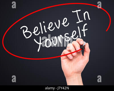 Man Hand writing Believe In Yourself with marker on transparent wipe board. Isolated on black. Business, internet, technology concept. Stock Photo Stock Photo