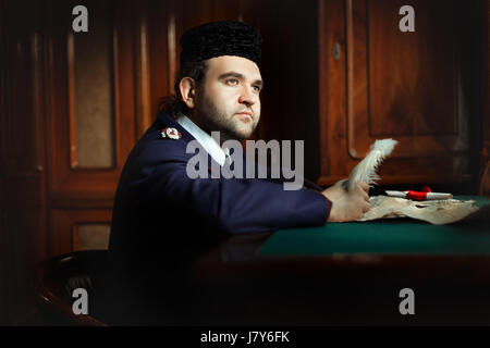 Man behind the desk writing pen. He writes in a retro form of the manuscript. Stock Photo