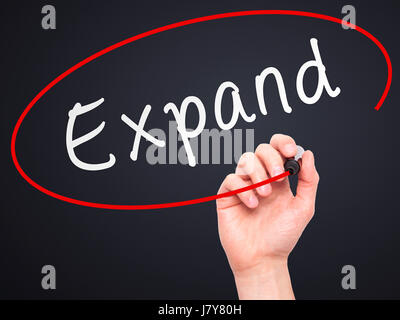 Man Hand writing Expand with marker on transparent wipe board. Isolated on black. Business, internet, technology concept.  Stock Photo Stock Photo