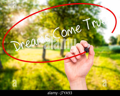Man Hand writing Dreams Come True with black marker on visual screen. Isolated on nature. Business, technology, internet concept. Stock Photo Stock Photo
