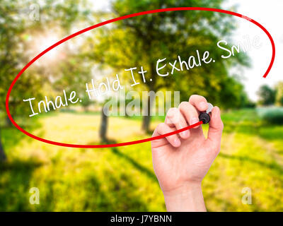 Man Hand writing Inhale Hold It Exhale Smile with black marker on visual screen. Isolated on nature. Business, technology, internet concept. Stock Pho Stock Photo