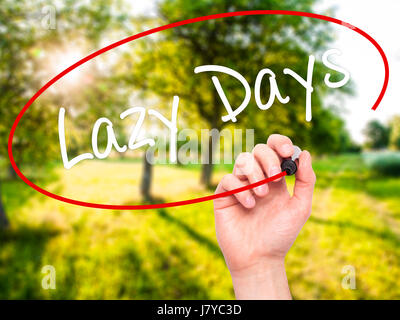 Man Hand writing Lazy Days with black marker on visual screen. Isolated on background. Business, technology, internet concept. Stock Photo Stock Photo