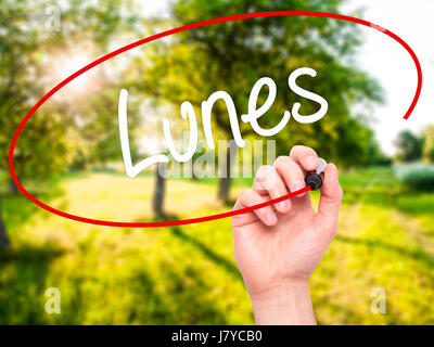 Man Hand writing Lunes (Monday in Spanish) with black marker on visual screen. Isolated on nature. Business, technology, internet concept. Stock Photo