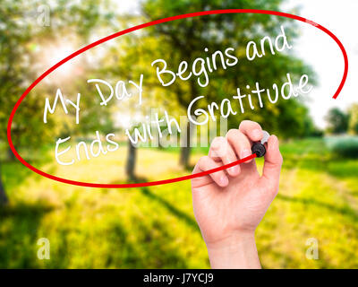 Man Hand writing My Day Begins and Ends with Gratitude with black marker on visual screen. Isolated on nature. Business, technology, internet concept. Stock Photo