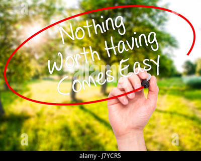 Man Hand writing Nothing Worth Having Comes Easy with black marker on visual screen. Isolated on background. Business, technology, internet concept. S Stock Photo