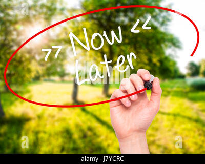 Man Hand writing Now/Later with black marker on visual screen. Isolated on background. Business, technology, internet concept. Stock Photo Stock Photo