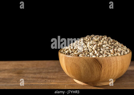 Close up millet rice or millet grains in bowl on wooden table. Isolated on black background Stock Photo