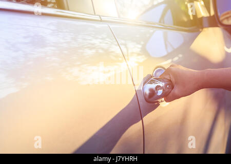 Close up woman hand opening car door. Shot at evening with lens flare effect Stock Photo