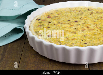 Quiche with cheese, bacon and mushroom on rustic wooden table - Open pie in white dish with selective focus Stock Photo