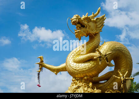 Giant golden Chinese dragon statue on blue sky background in Phuket Town, Thailand Stock Photo