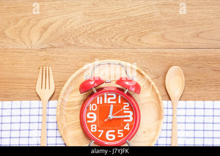 Top view red alarm clock in wooden dish, spoon and fork on wooden plank background. Time eating concept Stock Photo