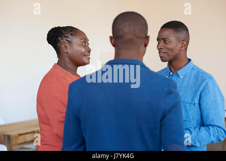 Three smiling African office colleagues talking together at work Stock Photo