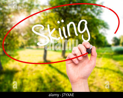 Man Hand writing Skiing with black marker on visual screen. Isolated on nature. Business, technology, internet concept. Stock Photo Stock Photo