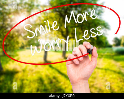 Man Hand writing Smile More Worry Less with black marker on visual screen. Isolated on background. Business, technology, internet concept. Stock Photo Stock Photo