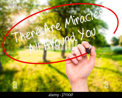 Man Hand writing There Are Miracles All Around You  with black marker on visual screen. Isolated on nature. Business, technology, internet concept. St Stock Photo
