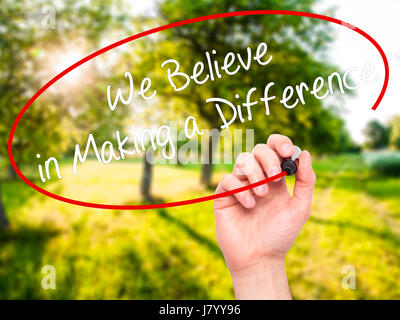 Man Hand writing We Believe in Making a Difference with black marker on visual screen. Isolated on background. Business, technology, internet concept. Stock Photo